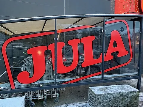 Stor JULA-logo montert på glassvegg ved inngang til handlekurvområde.