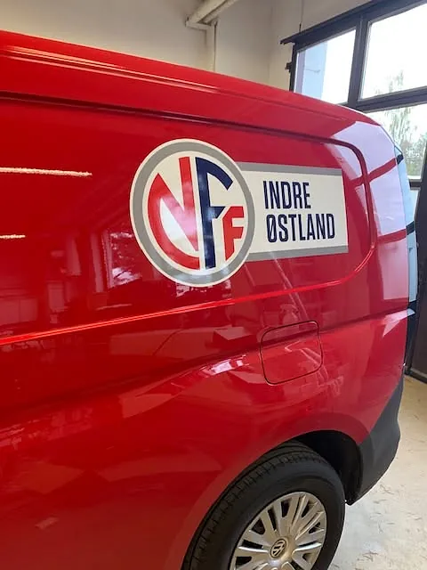 Rød varebil med logo for NFF Indre Østland montert som profilering på sidedør.