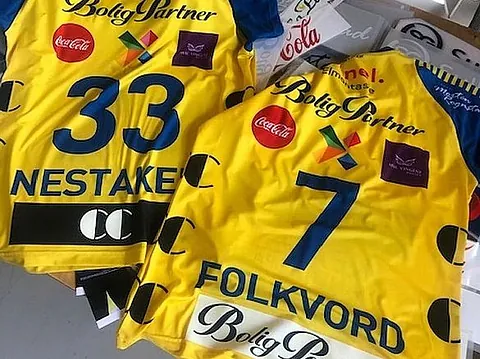Gule lagtrøyer med sponsormerker, navn og nummer produsert med tekstiltrykk.