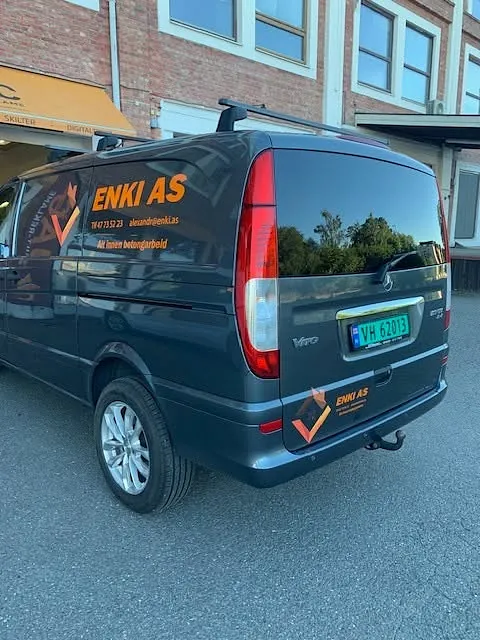 Sort varebil med firmaprofilering fra ENKI AS parkert utenfor JAC Skilt-Reklame.