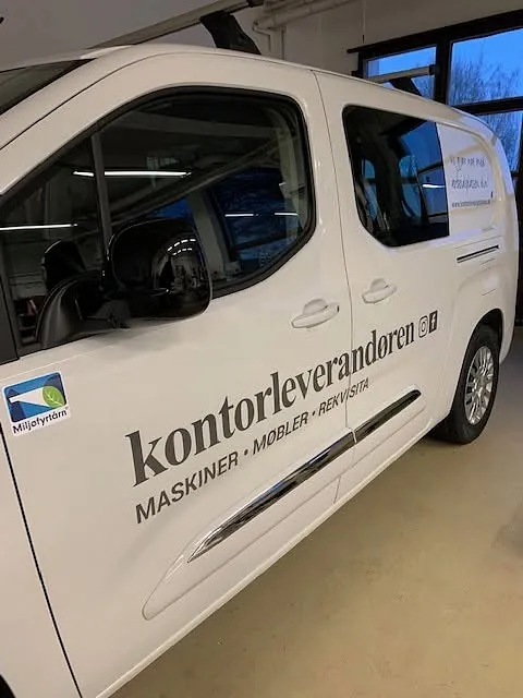 Hvit varebil med profilering for Kontorleverandøren, fotografert innendørs i verksted.