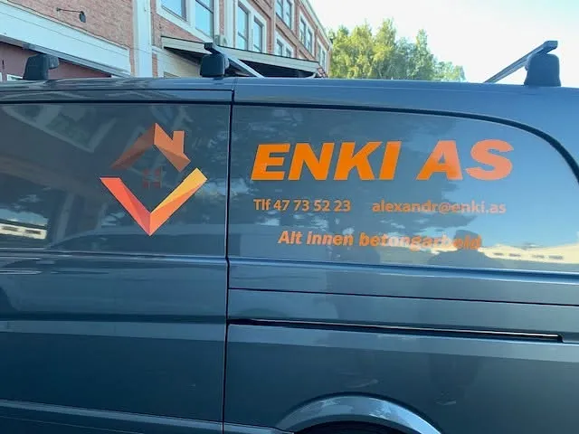 Nærbilde av sideprofilering på ENKI AS-varebil med logo og kontaktinformasjon.
