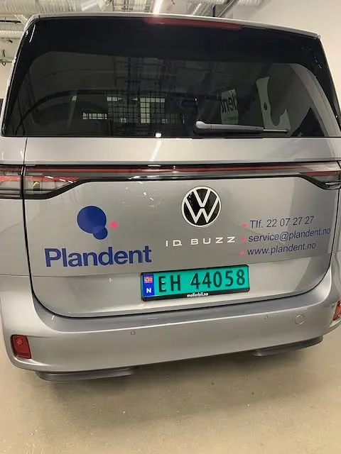 Bakside av elektrisk firmabil med Plandent-logo og kontaktinformasjon på foliering.