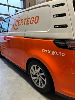Hvit og oransje firmabil med Certego-profilering og nettadresse på sidedør.