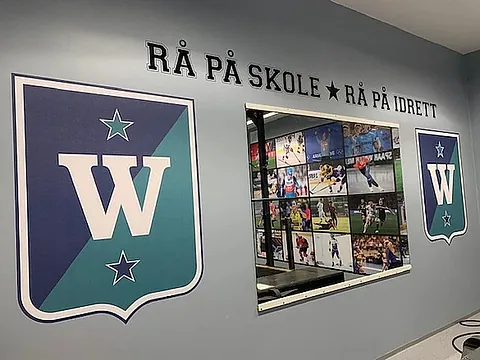 Veggdekor med W-logoer, bilder og teksten «RÅ PÅ SKOLE – RÅ PÅ IDRETT».